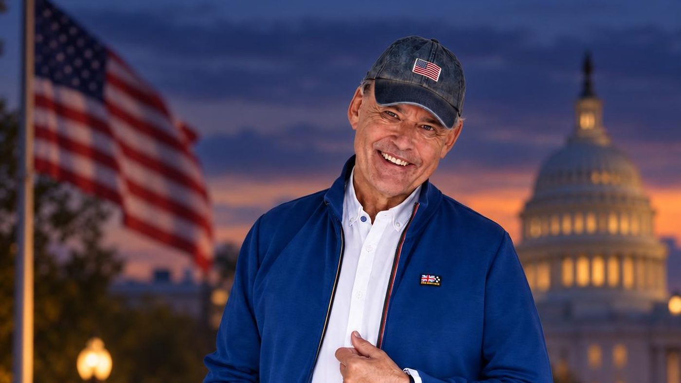 Charles Groenhuijsen met een pet met Amerikaanse vlag bij schemering in Washington, met de Amerikaanse vlag en het Capitool op de achtergrond